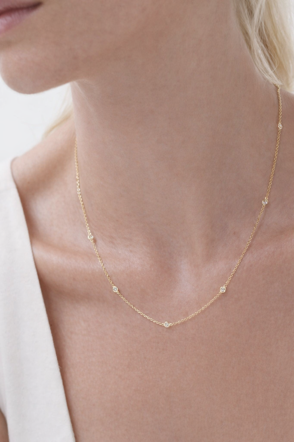 close-up image of ALVA Diamond Bezel Station Necklace in yellow gold on a model's neck 